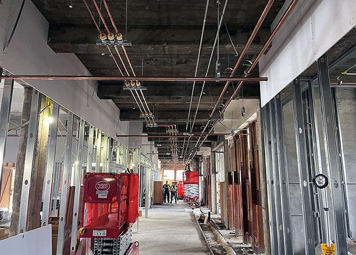 metal framing and wallboard in a hallway with copper pipes running across the ceiling space