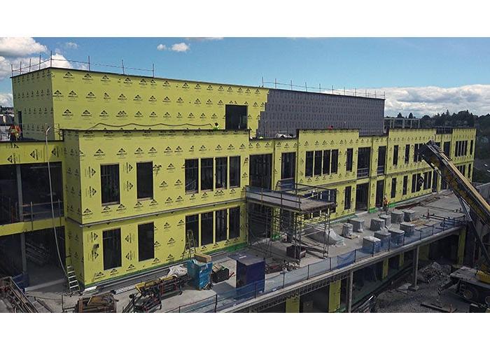 View of the top two stories and the mechanical penthouse of the new addition. below the 2nd floor windows, a large deck area is shown, which currently is holding construction materials